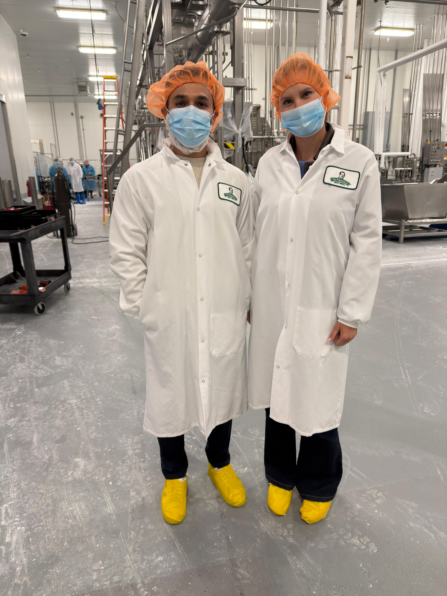 The Tribu founders in hairnets and lab coats on a cheese plant floor
